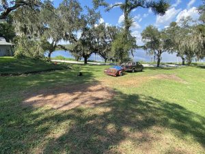 A truck parked on the grass beside a serene lake, surrounded by nature's beauty.